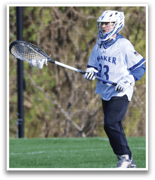A person wearing a white shirt and blue pants holding a lacrosse stick. Description generated by AI