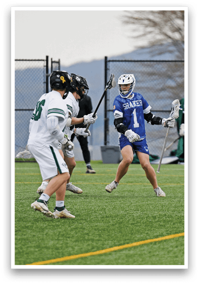 A man in a blue and white uniform is holding a stick and running on a field. Description generated by AI