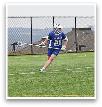 A man in a blue and white uniform is running with a stick in his hand. Description generated by AI