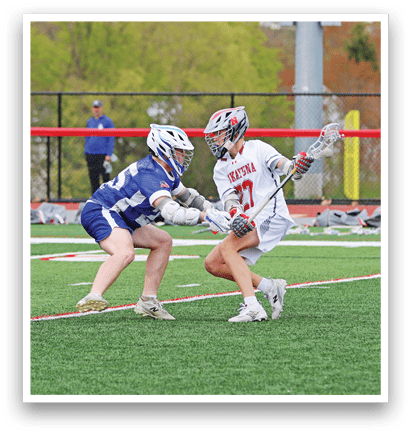 Two girls playing lacrosse on a field. Description generated by AI