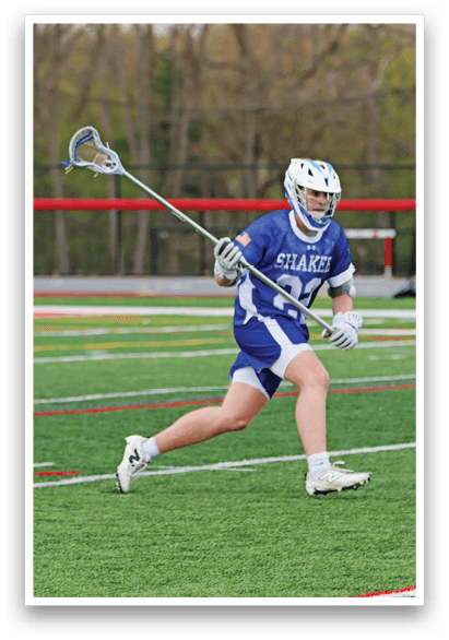 A man in a blue and white uniform is running with a lacrosse stick. Description generated by AI