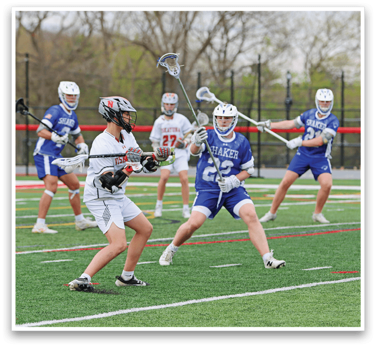 A group of people playing lacrosse on a field. Description generated by AI