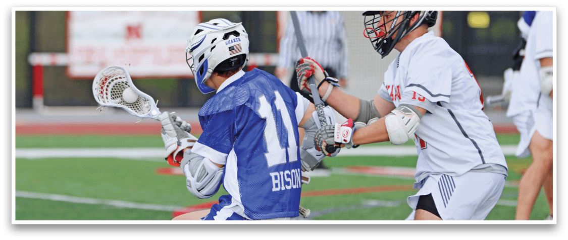 A boy in a blue and white uniform is playing lacrosse. Description generated by AI