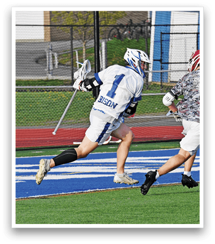 Two men playing lacrosse on a field. Description generated by AI