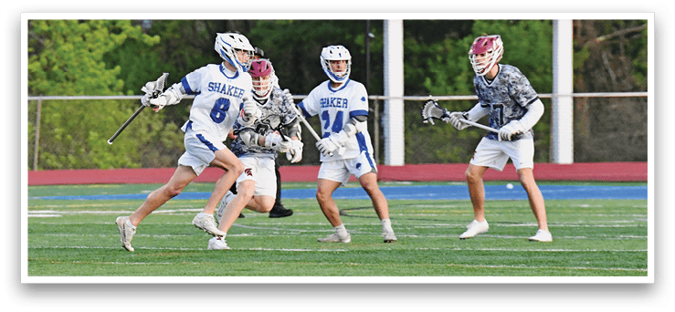 A group of people playing lacrosse on a field. Description generated by AI