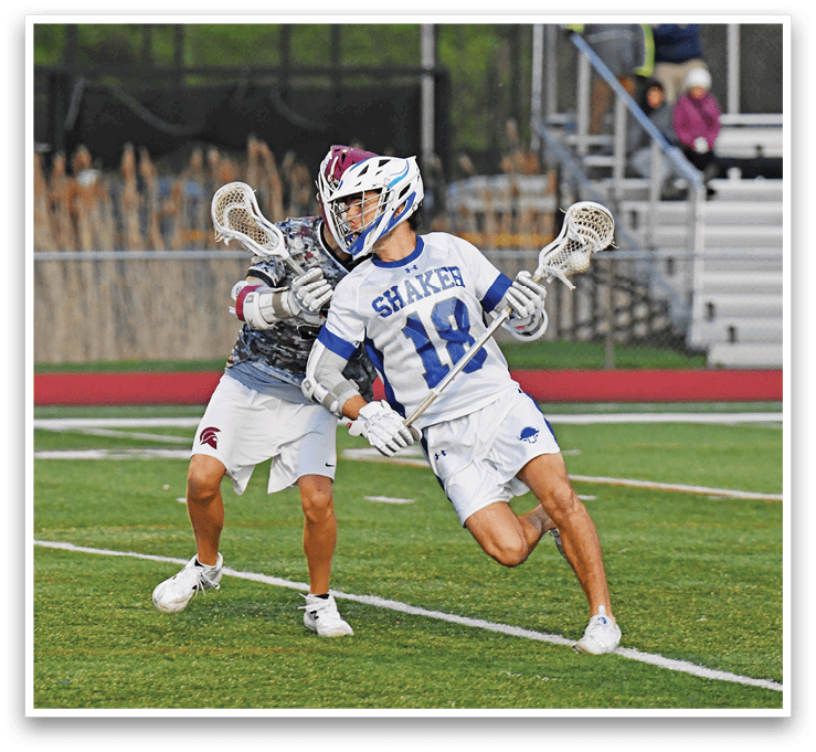 Two men playing lacrosse on a field. Description generated by AI