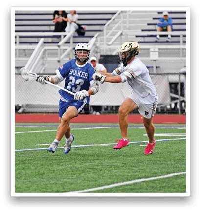 Two people playing lacrosse on a field. Description generated by AI