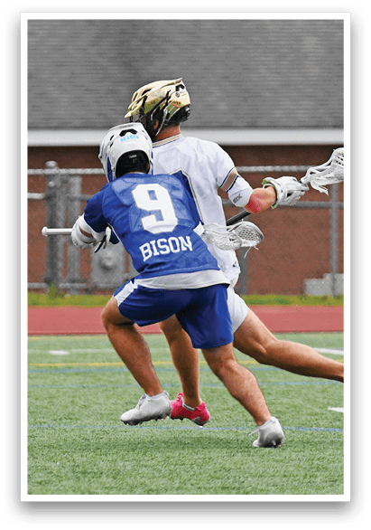 A man wearing a blue shirt and white shorts is playing lacrosse. Description generated by AI
