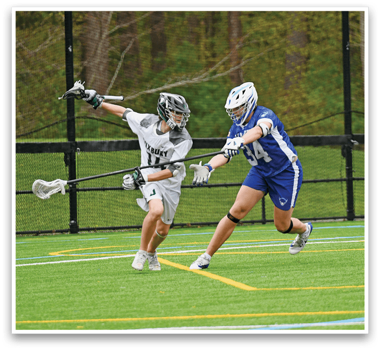 A man in a white and green shirt is holding a lacrosse stick. Description generated by AI