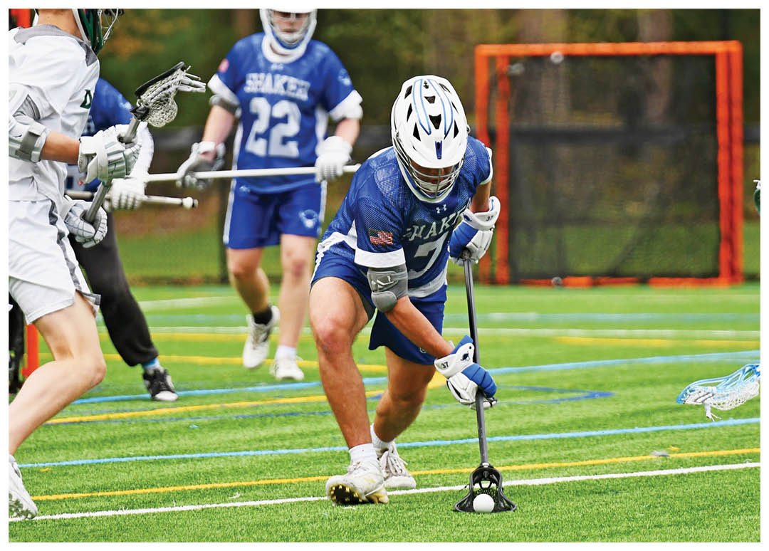 A group of people playing lacrosse on a field. Description generated by AI