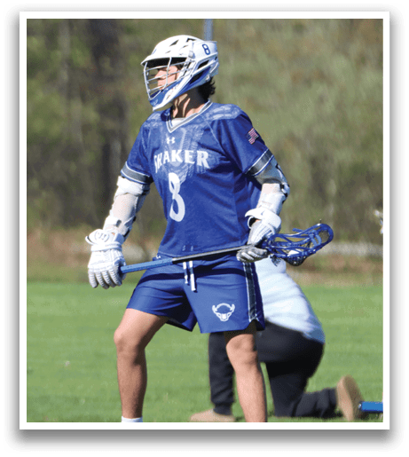 A man wearing a blue and white jersey holding a lacrosse stick. Description generated by AI