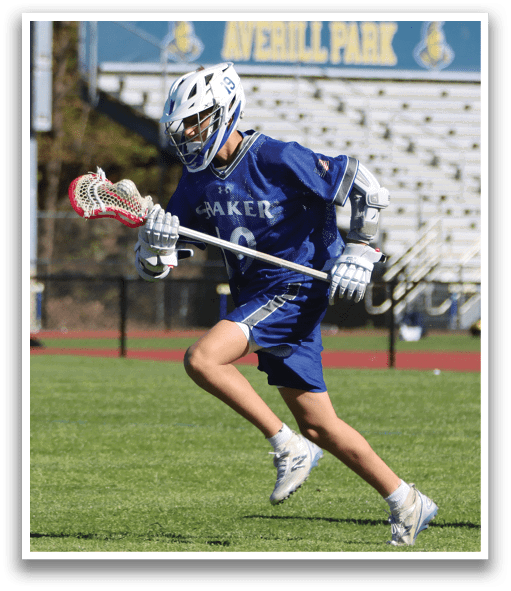 A boy running on a field with a blue and white jersey on. Description generated by AI