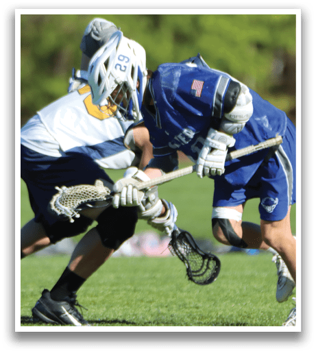 Two boys playing lacrosse on a field. Description generated by AI