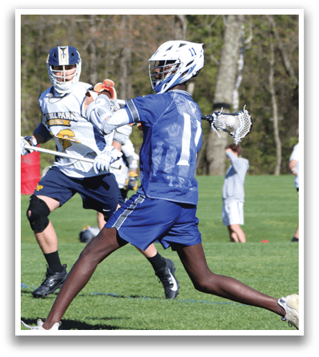 A man wearing a blue shirt and black shorts is playing lacrosse. Description generated by AI
