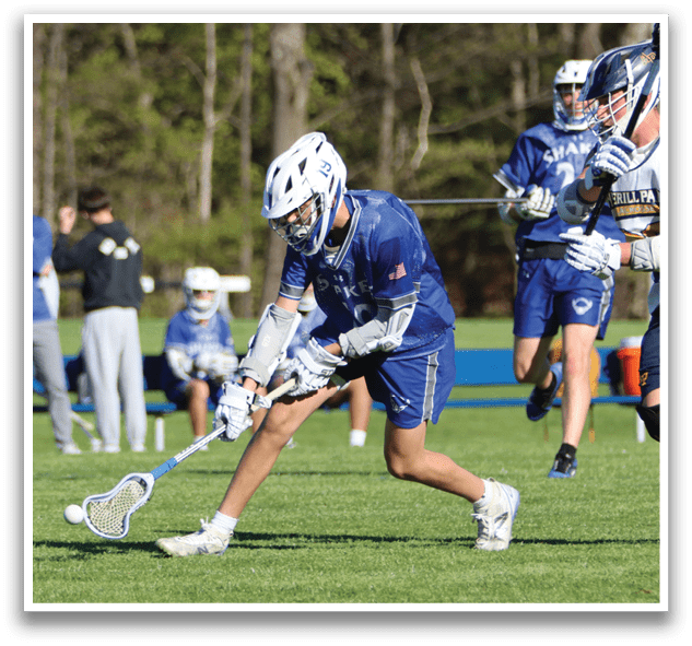 A boy in a blue and white uniform is holding a stick and running on a field. Description generated by AI