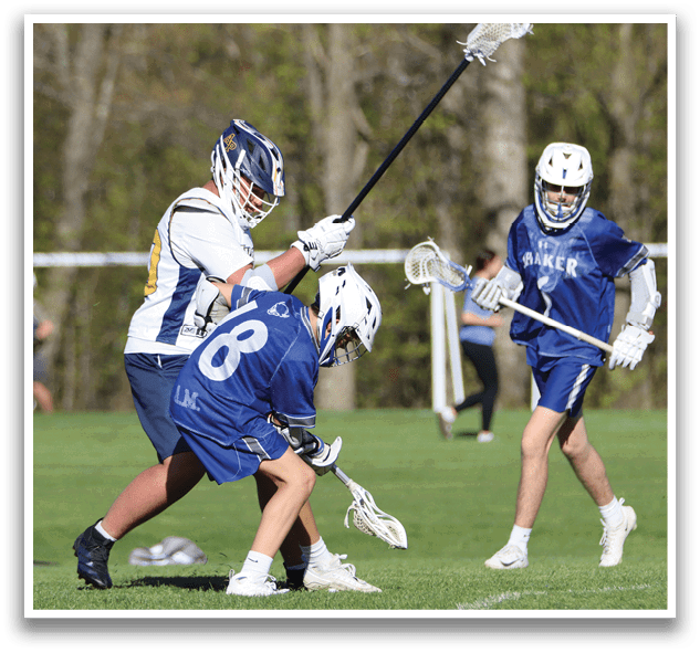 A man in a blue shirt is holding a lacrosse stick. Description generated by AI