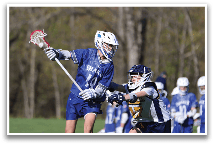 A boy in a blue and white uniform is holding a lacrosse stick. Description generated by AI