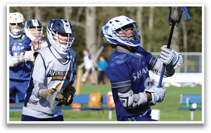 A man wearing a blue shirt and holding a lacrosse stick. Description generated by AI