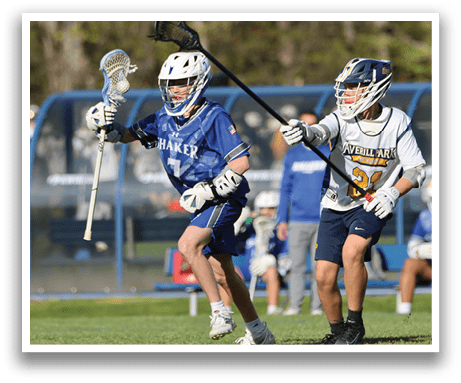 A boy in a blue and white uniform is holding a lacrosse stick. Description generated by AI