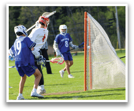 A boy in a blue shirt is playing lacrosse. Description generated by AI