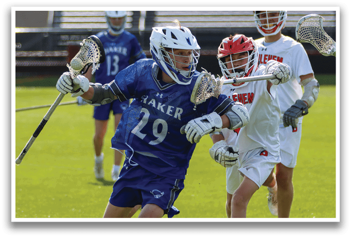 A boy in a blue and white uniform is running with a lacrosse stick. Description generated by AI