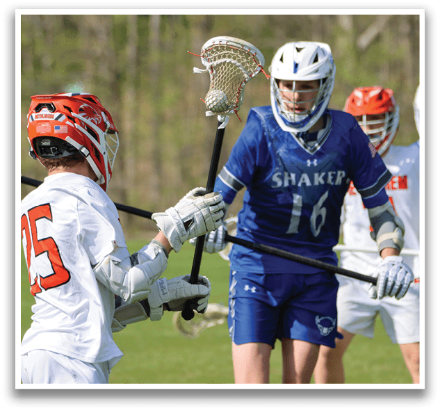A man wearing a blue and white uniform holding a lacrosse stick. Description generated by AI