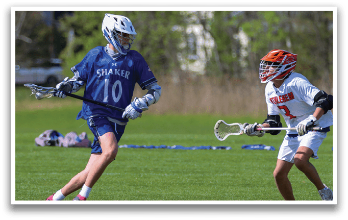 A boy in a blue and white uniform is running with a lacrosse stick. Description generated by AI