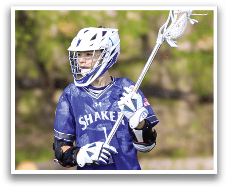 A man wearing a blue and white jersey holding a lacrosse stick. Description generated by AI