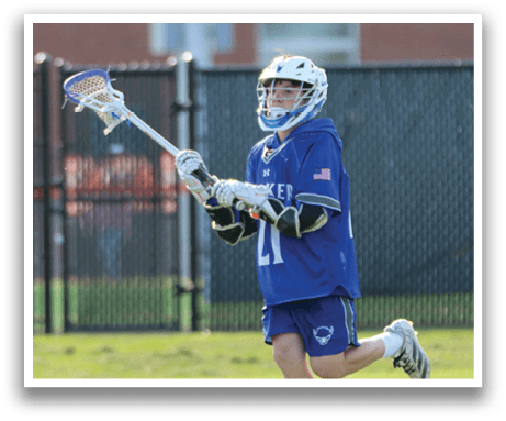 A young boy wearing a blue and white jersey is holding a lacrosse stick. Description generated by AI