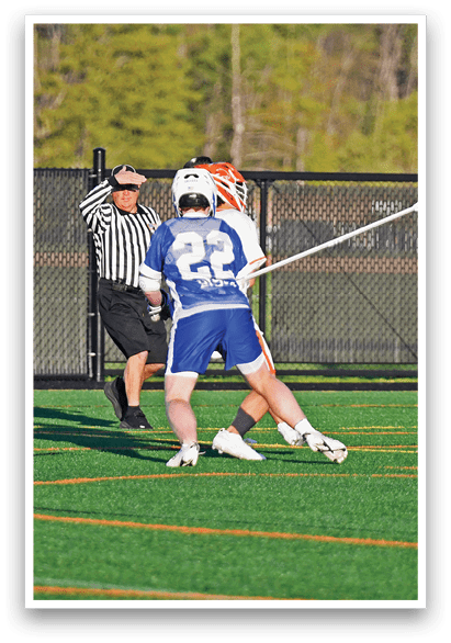 A man wearing a blue shirt and white shorts is playing lacrosse. Description generated by AI