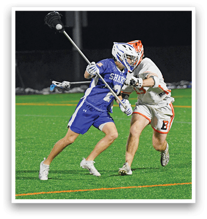 Two people playing lacrosse on a field. Description generated by AI