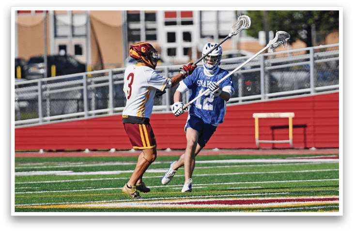 A man in a blue shirt and red shorts is playing lacrosse. Description generated by AI