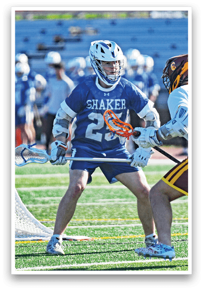 A man wearing a blue shirt and white pants is playing lacrosse. Description generated by AI