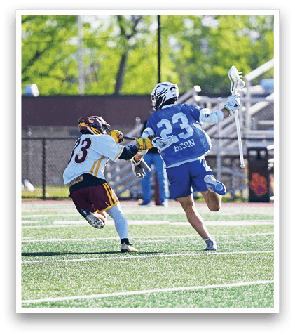 A man in a blue jersey is running with a lacrosse stick. Description generated by AI
