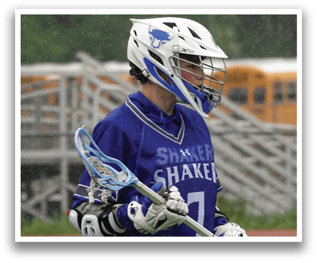 A man wearing a blue and white shirt holding a lacrosse stick. Description generated by AI