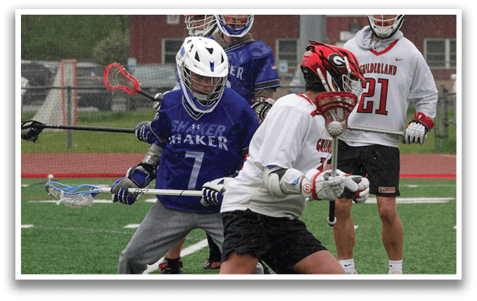 A group of people playing lacrosse on a field. Description generated by AI
