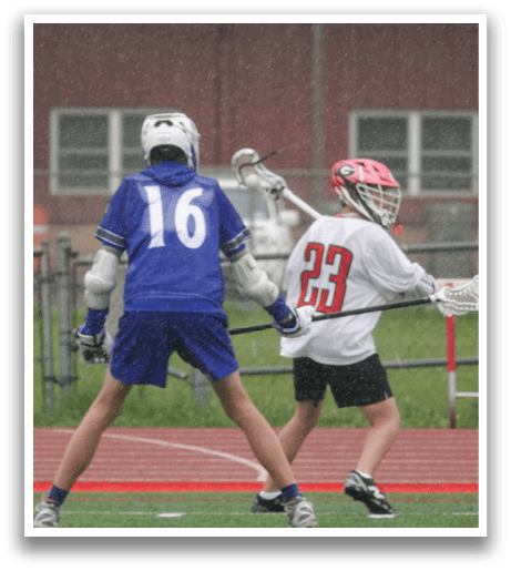 A boy in a blue and white shirt is playing lacrosse. Description generated by AI