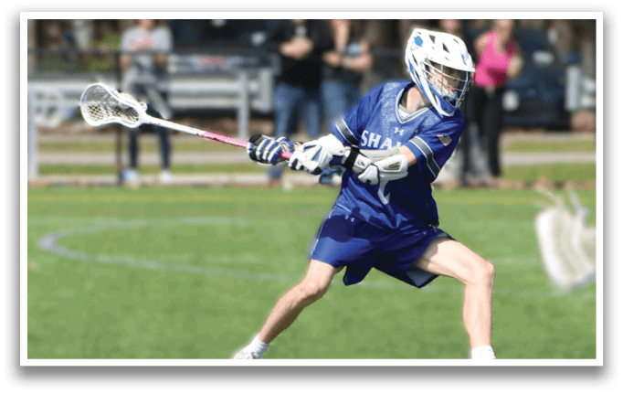 A man wearing a blue and white shirt and blue shorts is playing lacrosse. Description generated by AI