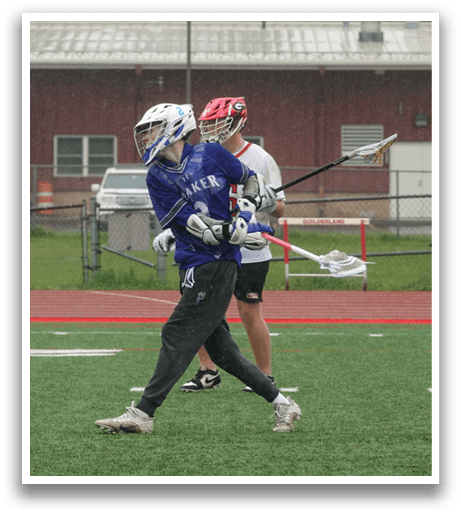 A man in a blue and white jersey is holding a lacrosse stick. Description generated by AI