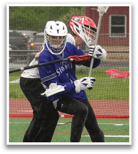 Two people playing lacrosse on a field. Description generated by AI