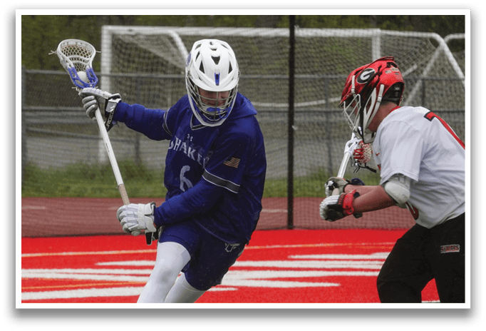 A man wearing a blue and white uniform is holding a lacrosse stick. Description generated by AI