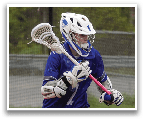 A man wearing a blue and white shirt and grey pants is running with a lacrosse stick. Description generated by AI