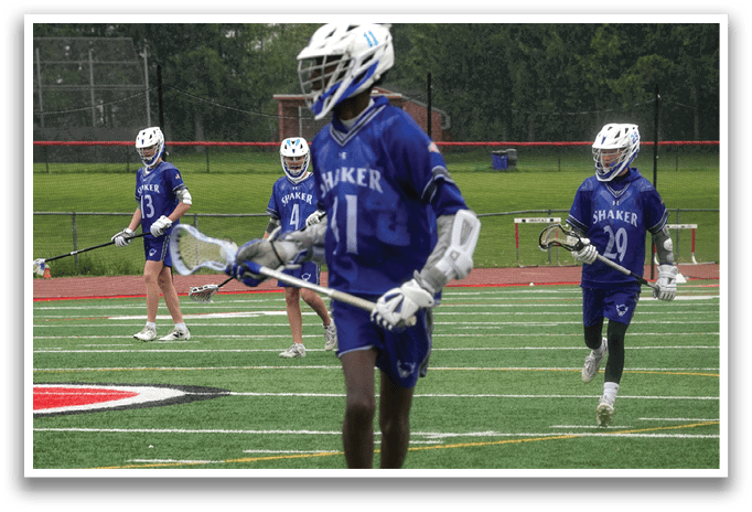 A group of people playing lacrosse on a field. Description generated by AI