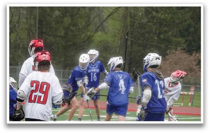 A group of young men playing lacrosse on a field. Description generated by AI