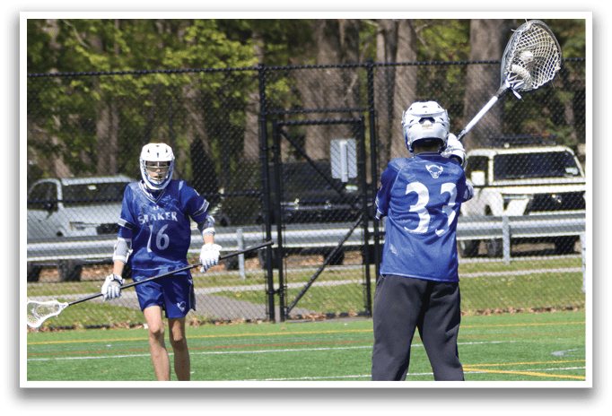 A man wearing a blue shirt and black pants is holding a lacrosse stick. Description generated by AI