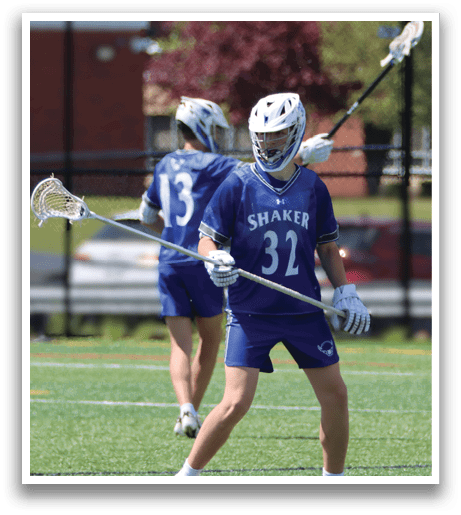 A man wearing a blue and white uniform holding a lacrosse stick. Description generated by AI