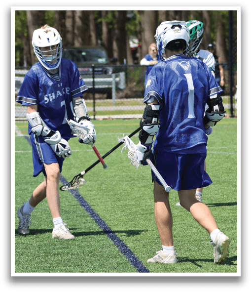 Two men playing lacrosse on a field. Description generated by AI