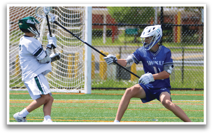 A man in a blue and white uniform is holding a lacrosse stick. Description generated by AI