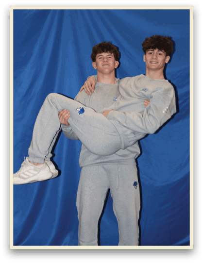 Two young men are posing for a picture, one of them is holding the other's legs. AI generated content