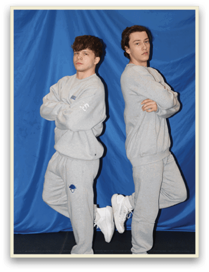 Two young men wearing gray sweatsuits pose for a picture. AI generated content